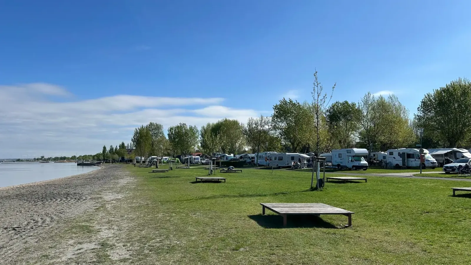 Wohnwagen auf der Wiese am Ufer des Strandcamping Podersdorf