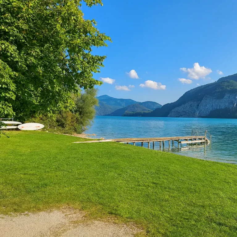 Badestrand am Paradiescamping Wolfgangsee: flacher Einstieg, Holzsteg und klare Sicht ins türkisfarbene Wasser