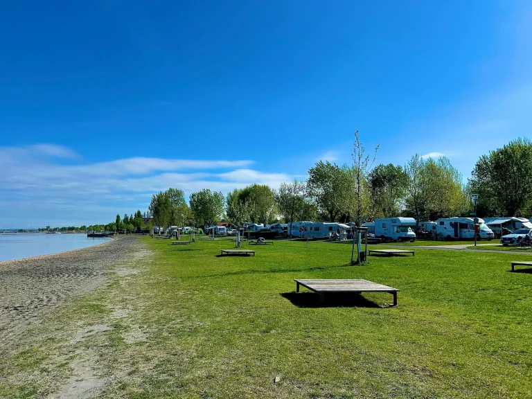 Campingplatz am See mit vielen Wohnmobilen, blauer Himmel – Inspiration für Kurzurlaube an Fenstertage/Zwickeltage in Österreich 2026