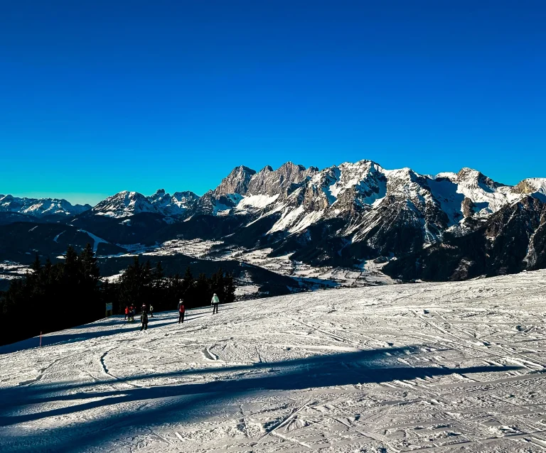 Winter-Camping: Blick auf Skipiste mit Bergen im Hintergrund an einem wolkenlosen Tag