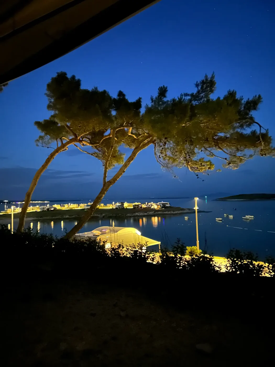 Nächtlicher Ausblick von unserer erhöhten Luxury-Parzelle im Camping Arena Stupice auf die beleuchtete Bucht und das ruhige Meer