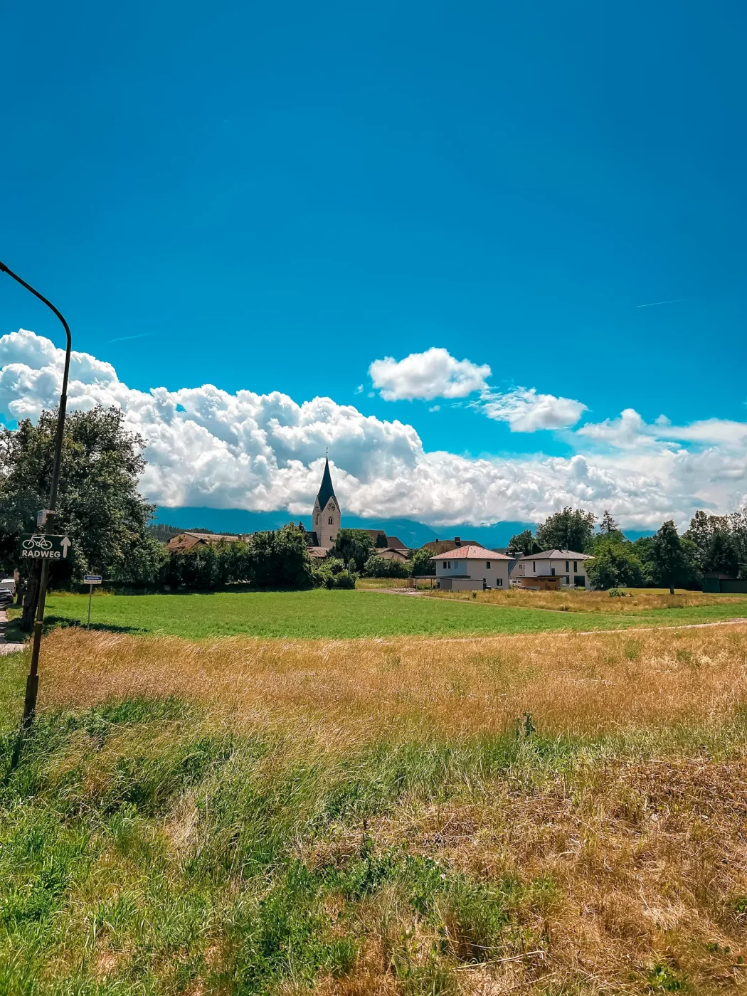Radweg bei Maria Gail mit Kirche, Feldern und Bergen im Hintergrund